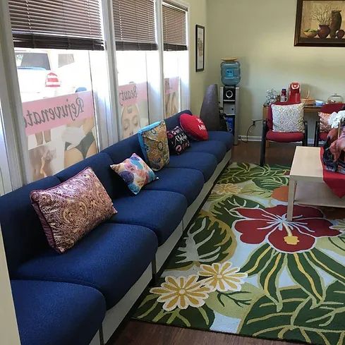 A living room with blue couches , chairs , a rug and a coffee table.