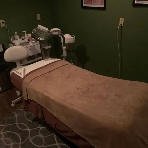 A massage table with a brown blanket in a room with green walls.