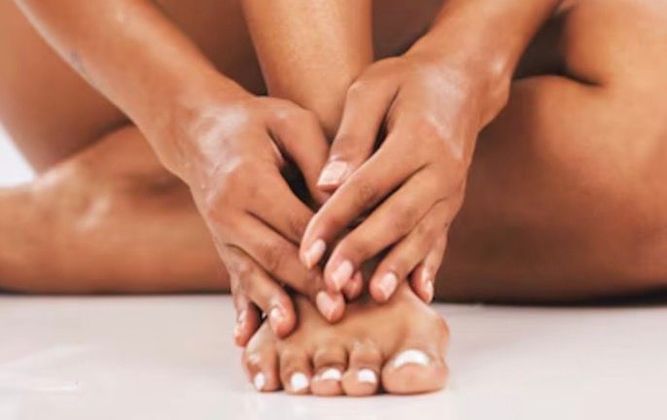A woman is sitting on the floor with her feet on a towel