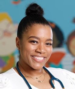 Woman with a stethoscope smiles in front of a colorful backdrop.