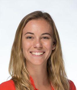 Woman with blonde hair smiling, wearing a red shirt, against a white background.