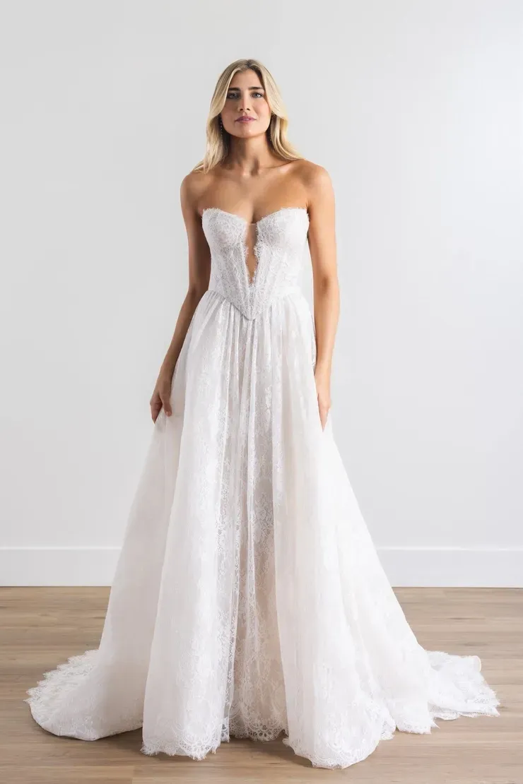 A woman in a white wedding dress is standing on a wooden floor.
