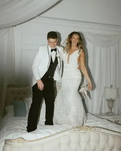 A bride and groom are posing for a picture on a bed.
