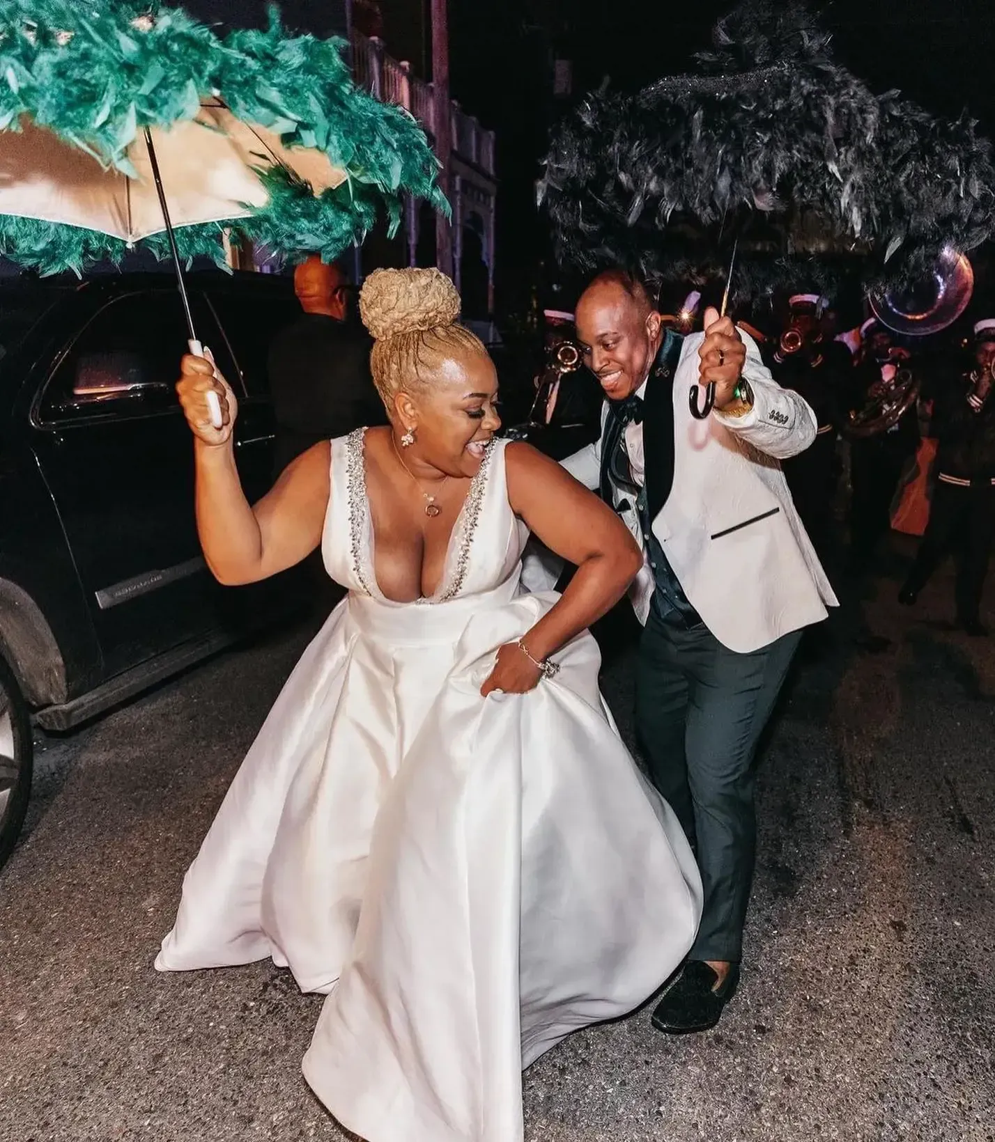A bride and groom are walking under an umbrella