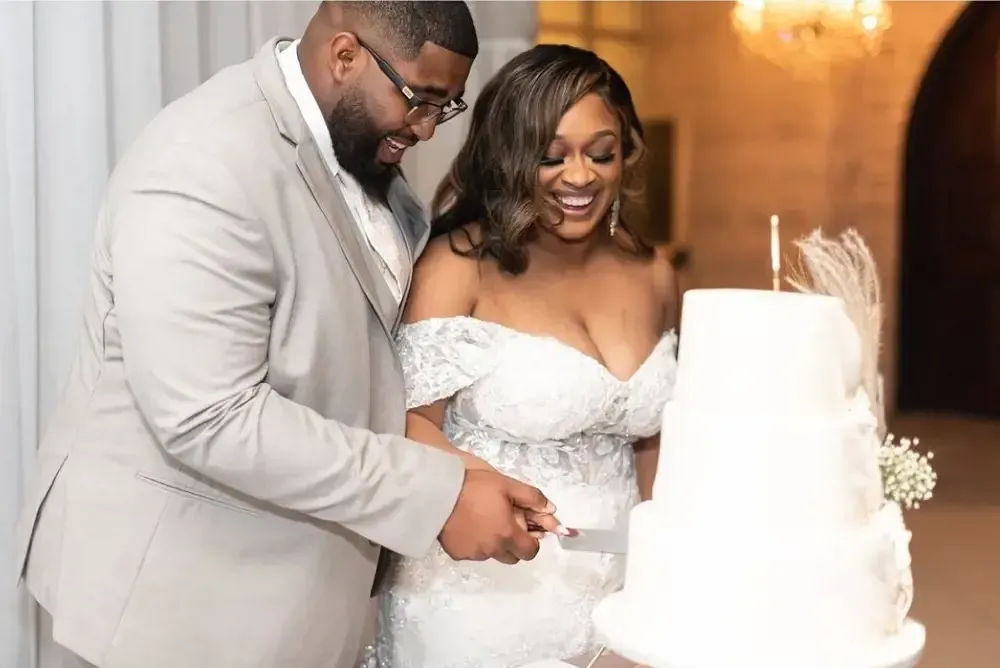 A bride and groom are cutting their wedding cake together.
