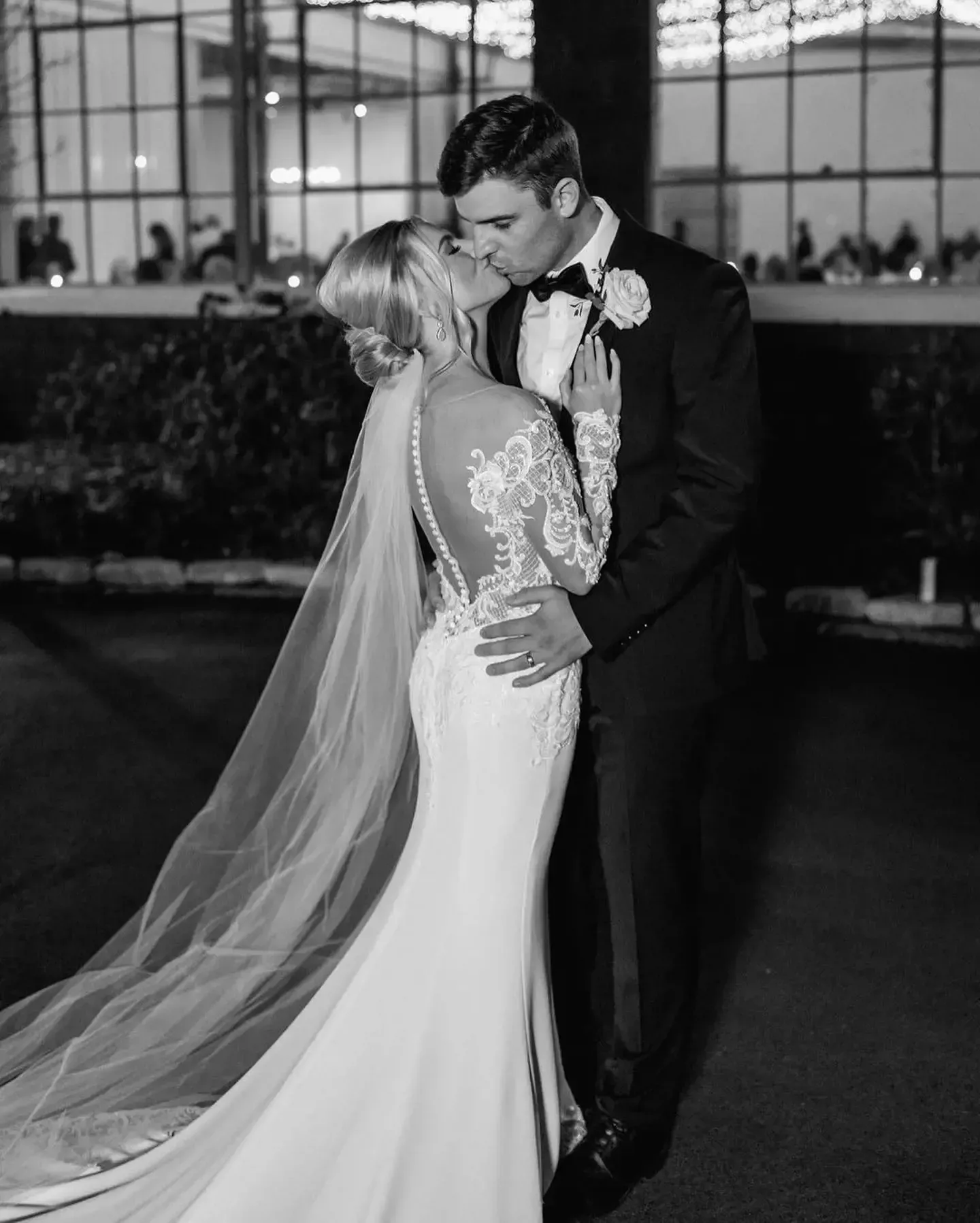 A bride and groom are kissing in a black and white photo.