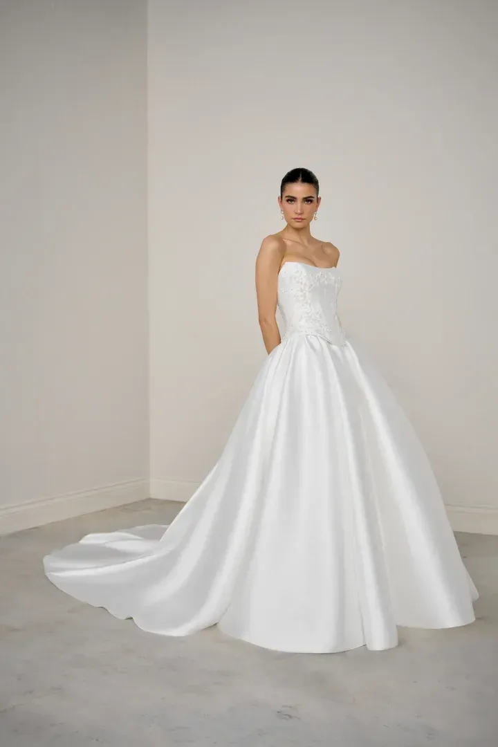 A woman is wearing a white strapless wedding dress with a high slit.