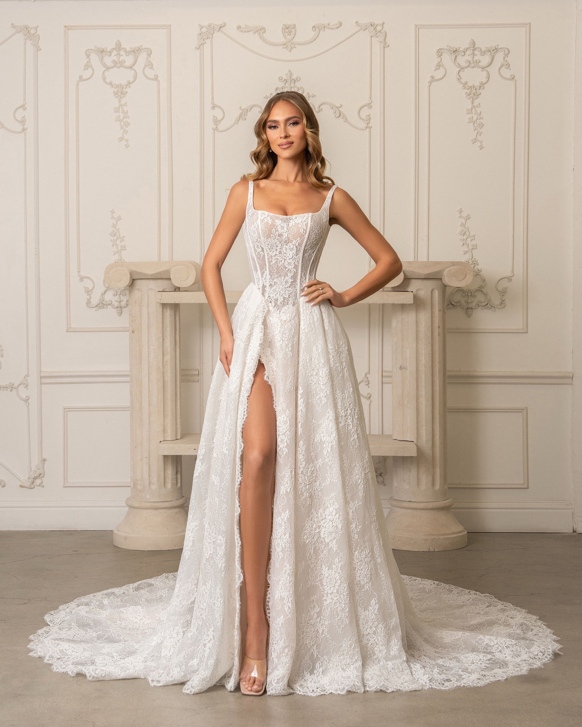 A woman in a white wedding dress is standing next to a table.