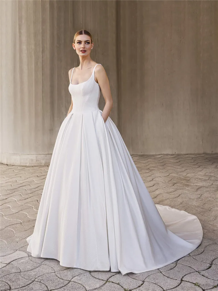 Woman in white wedding dress with pockets, standing outside.