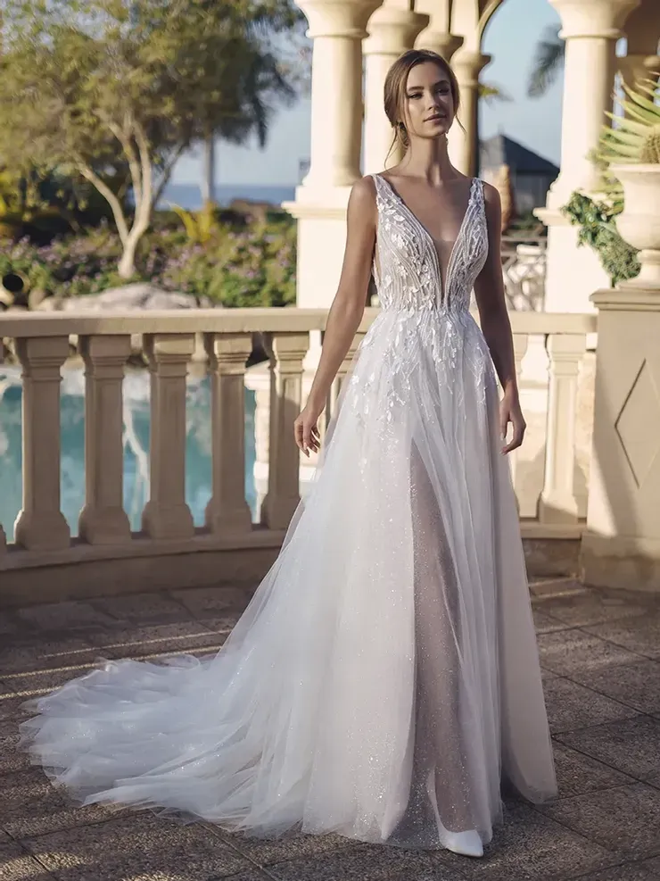 A woman in a white wedding dress is standing in front of a pool.