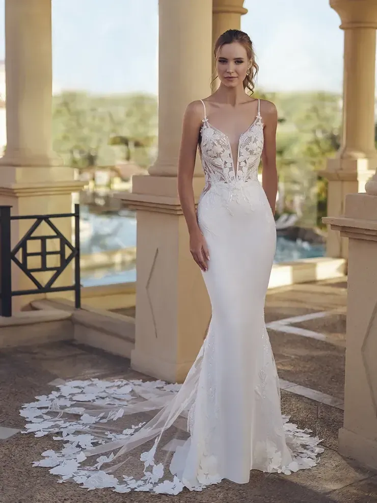 A woman in a white wedding dress is standing in front of a pool.