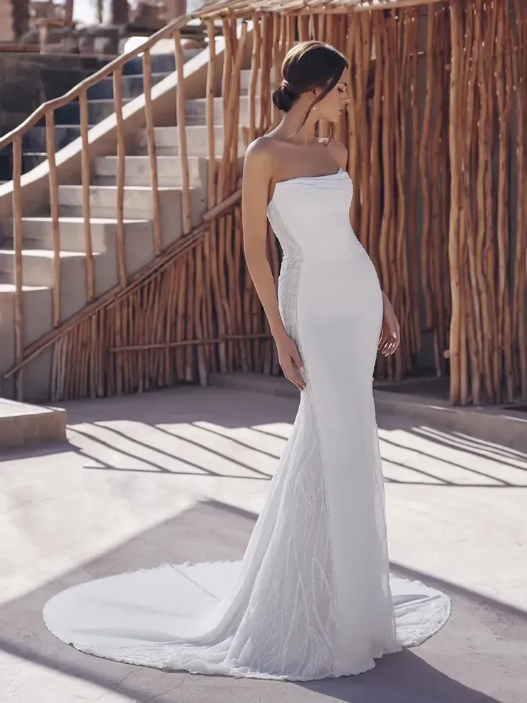 A woman in a white wedding dress is standing in front of stairs.