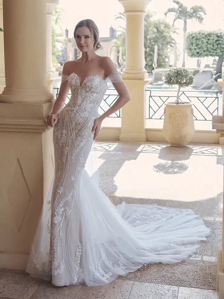 A woman in a wedding dress is leaning against a wall.