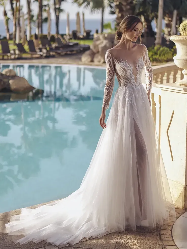 A woman in a wedding dress is standing next to a pool.