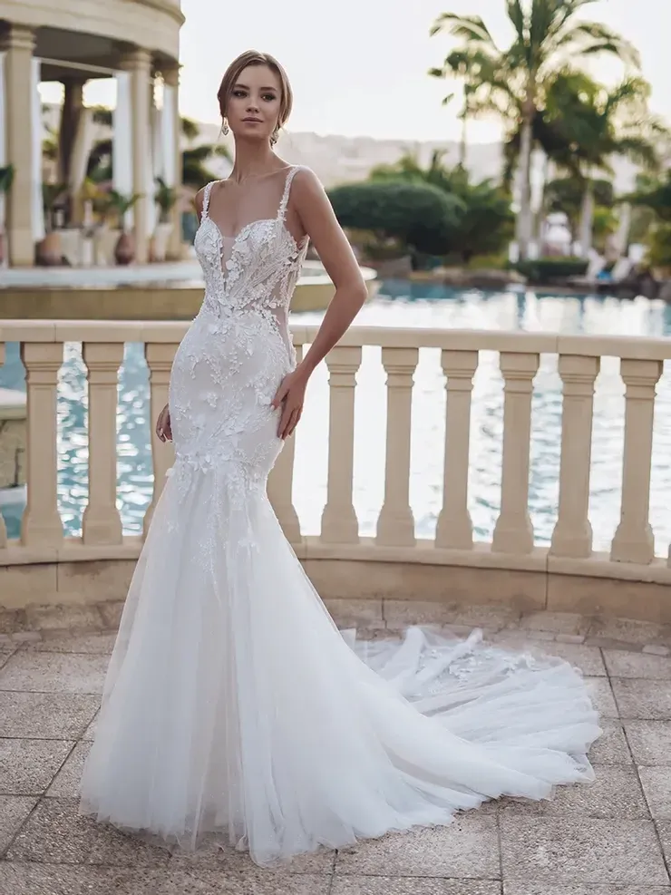 A woman in a white wedding dress is standing next to a pool.