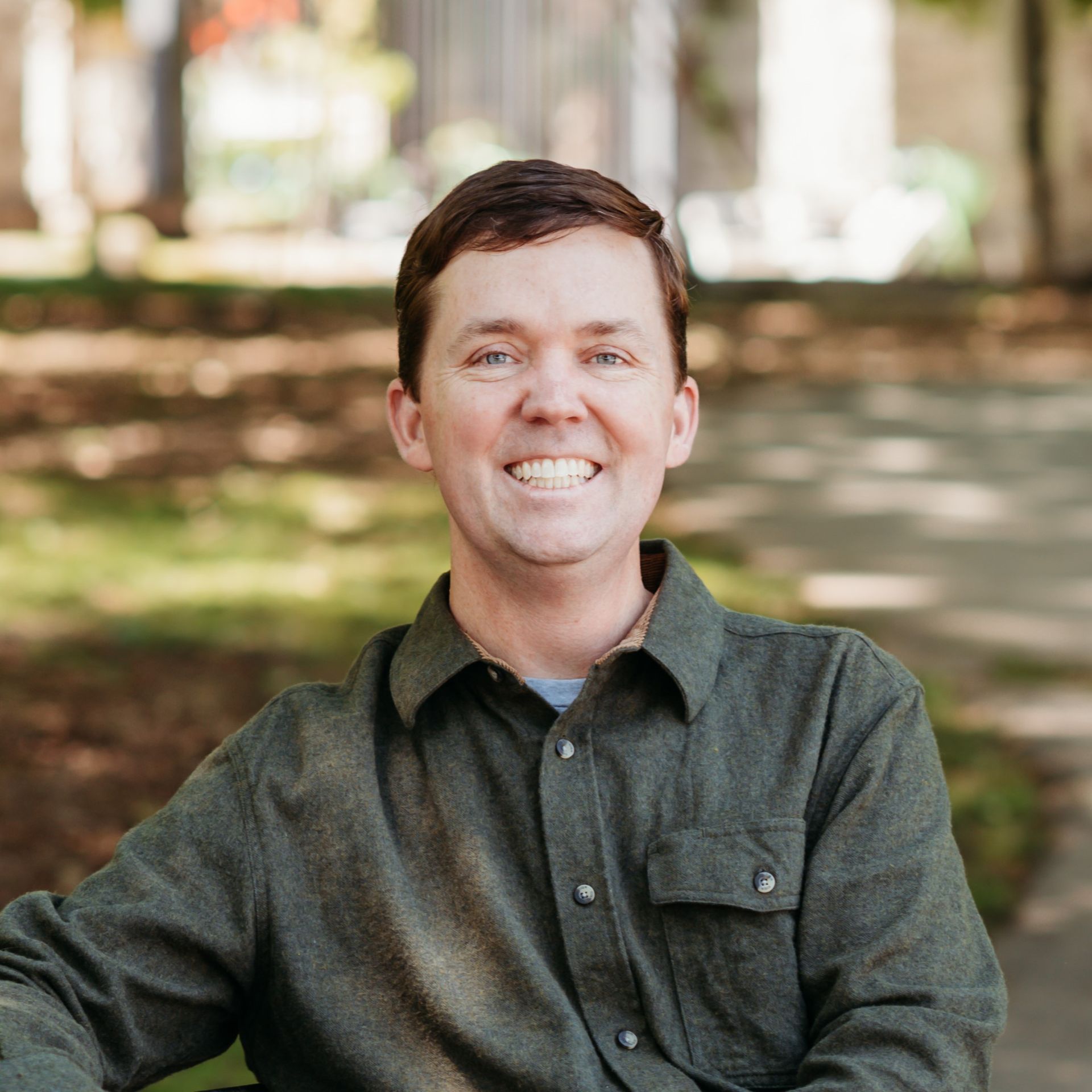 A man in a green shirt is smiling for the camera.