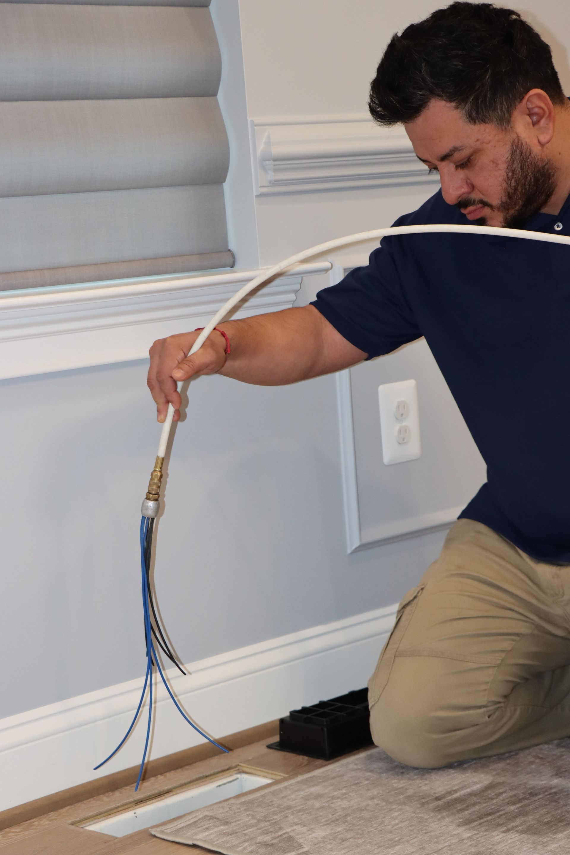 Person holding a green, brush-like tool to clean a ceiling vent.