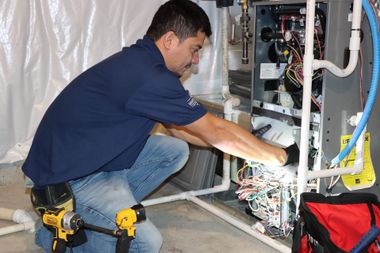 HVAC units stacked in a utility room, with ductwork and a black support frame.