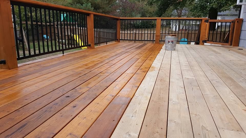 A wooden deck with a black railing is being painted.