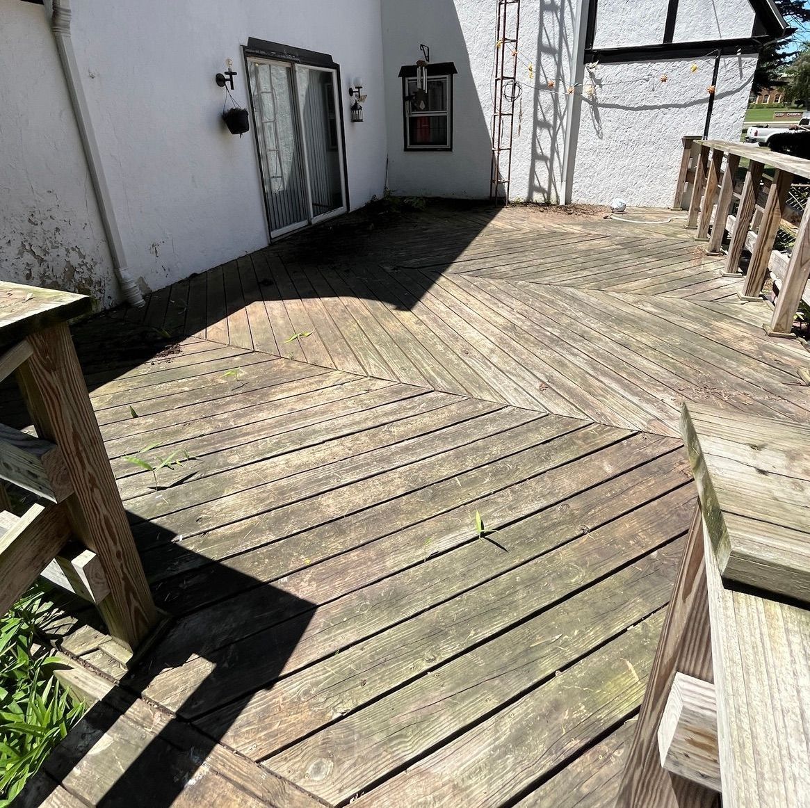 A wooden deck is sitting in front of a white house.