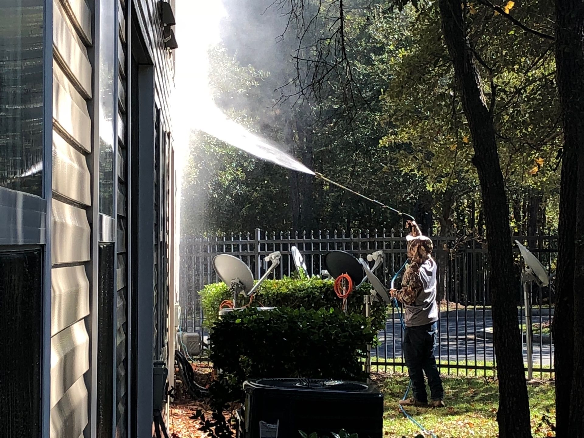 A man is spraying water on the side of a building.