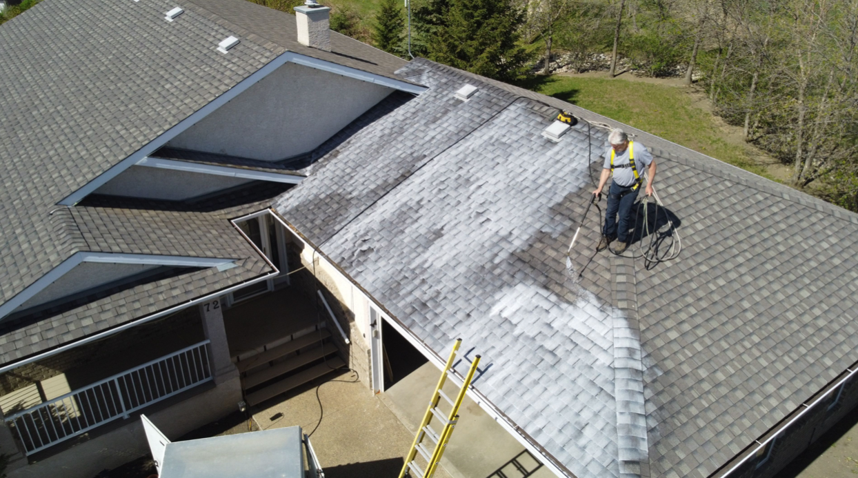 An aerial view of a man cleaning the roof of a house.
