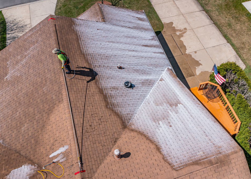 An aerial view of a man cleaning the roof of a house.