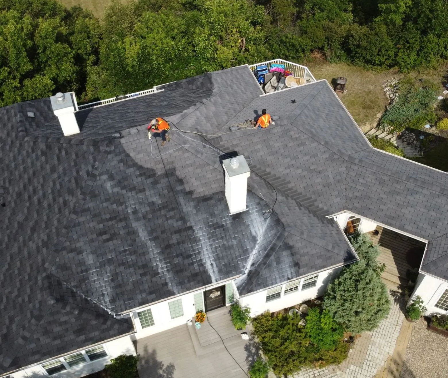 An aerial view of a house with people working on the roof.