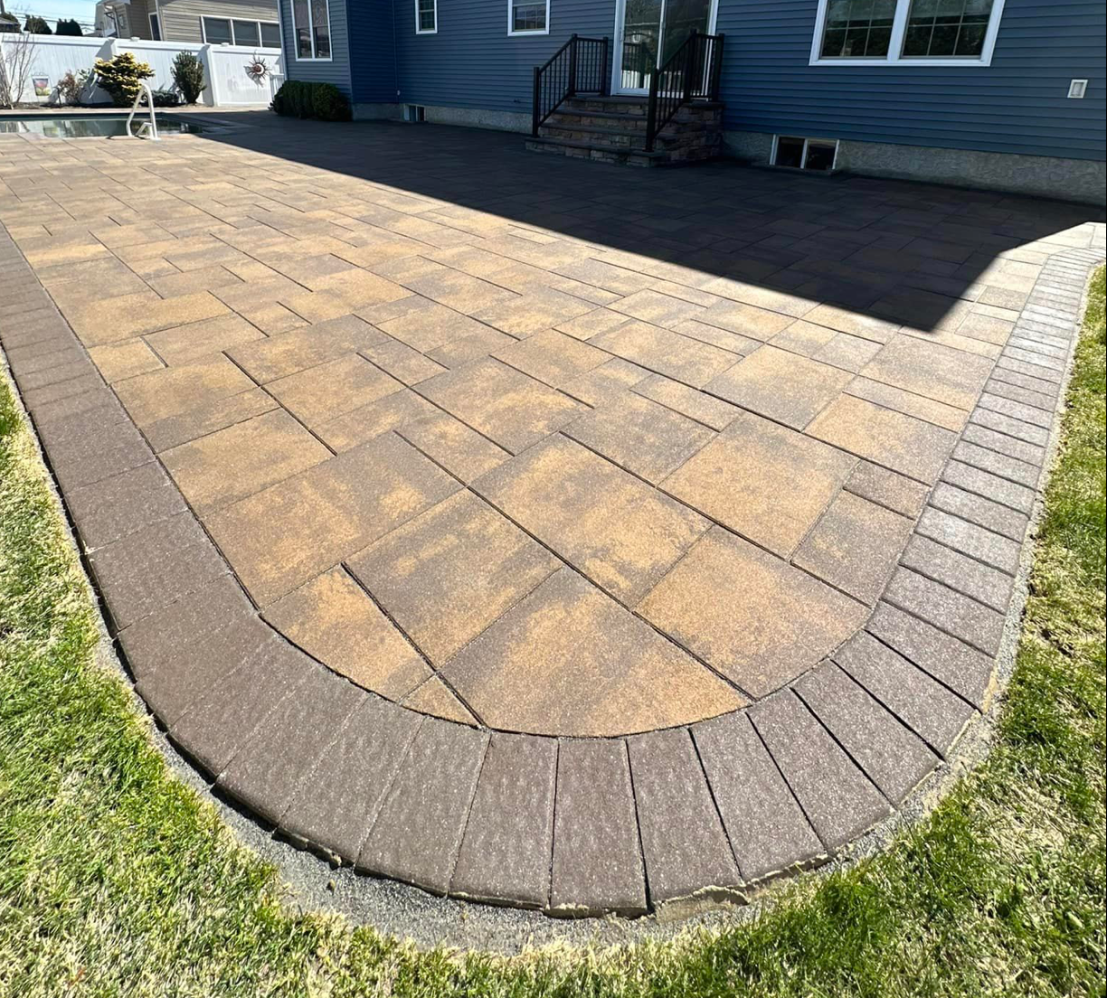A large brick patio in front of a house.
