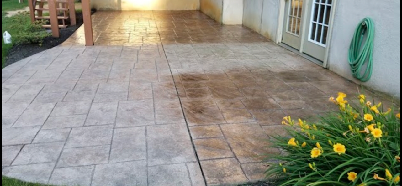 A patio with flowers and a hose on the side of it.
