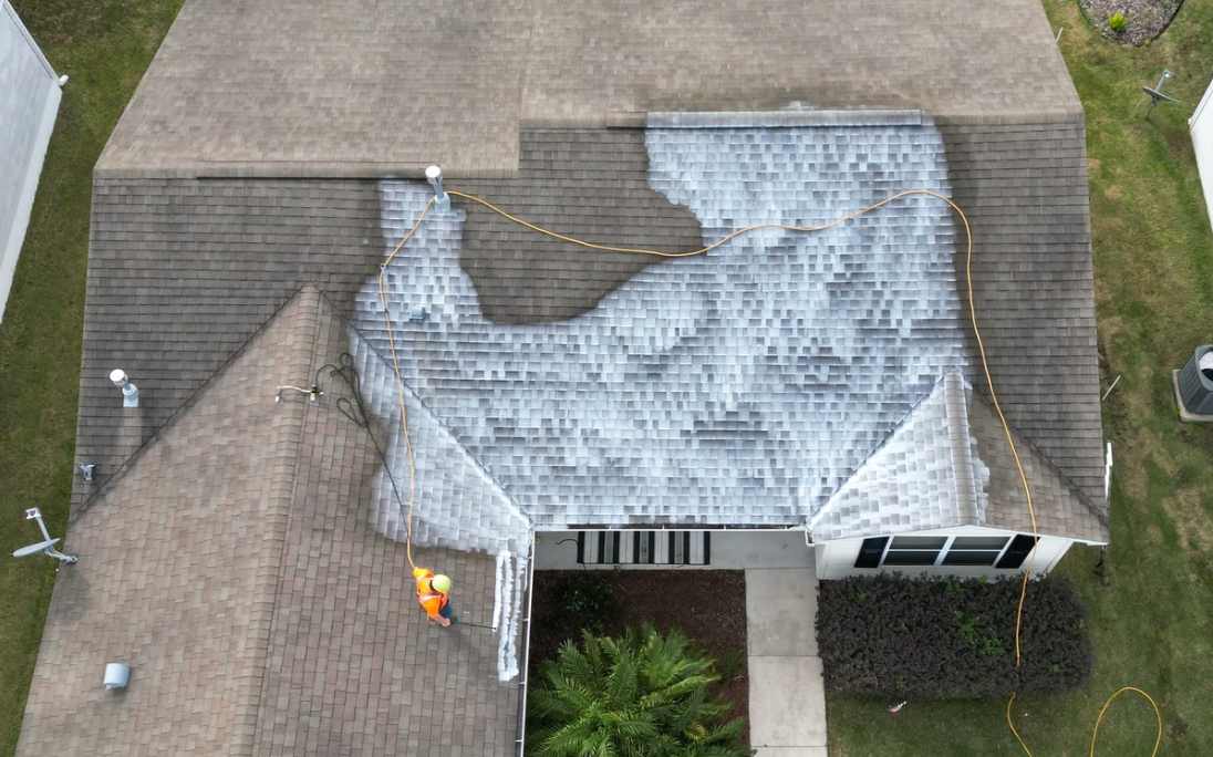 An aerial view of a house with a roof that has been damaged by a storm.