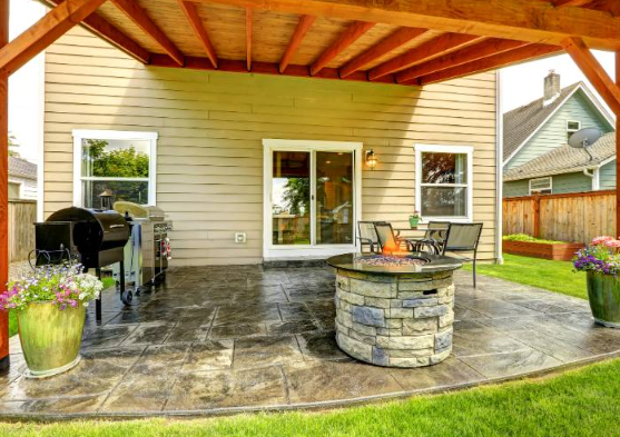 There is a fire pit on the patio under a pergola.