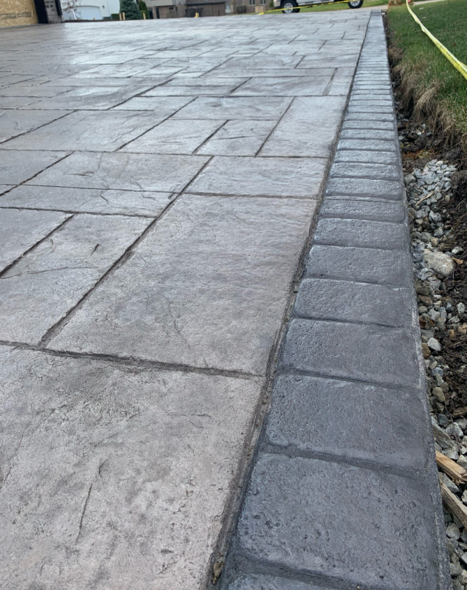 A concrete driveway is being built next to a grassy area.