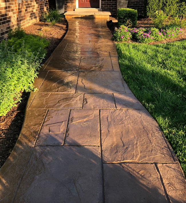 A concrete walkway leading to a brick house