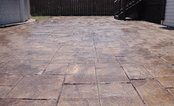 A concrete driveway with a wooden fence in the background
