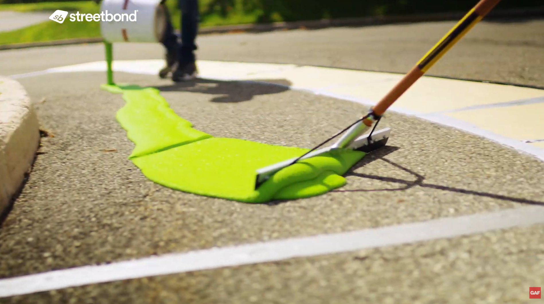 Person applying bright green coating to asphalt with a squeegee. Person applying bright green coating to asphalt with a squeegee.