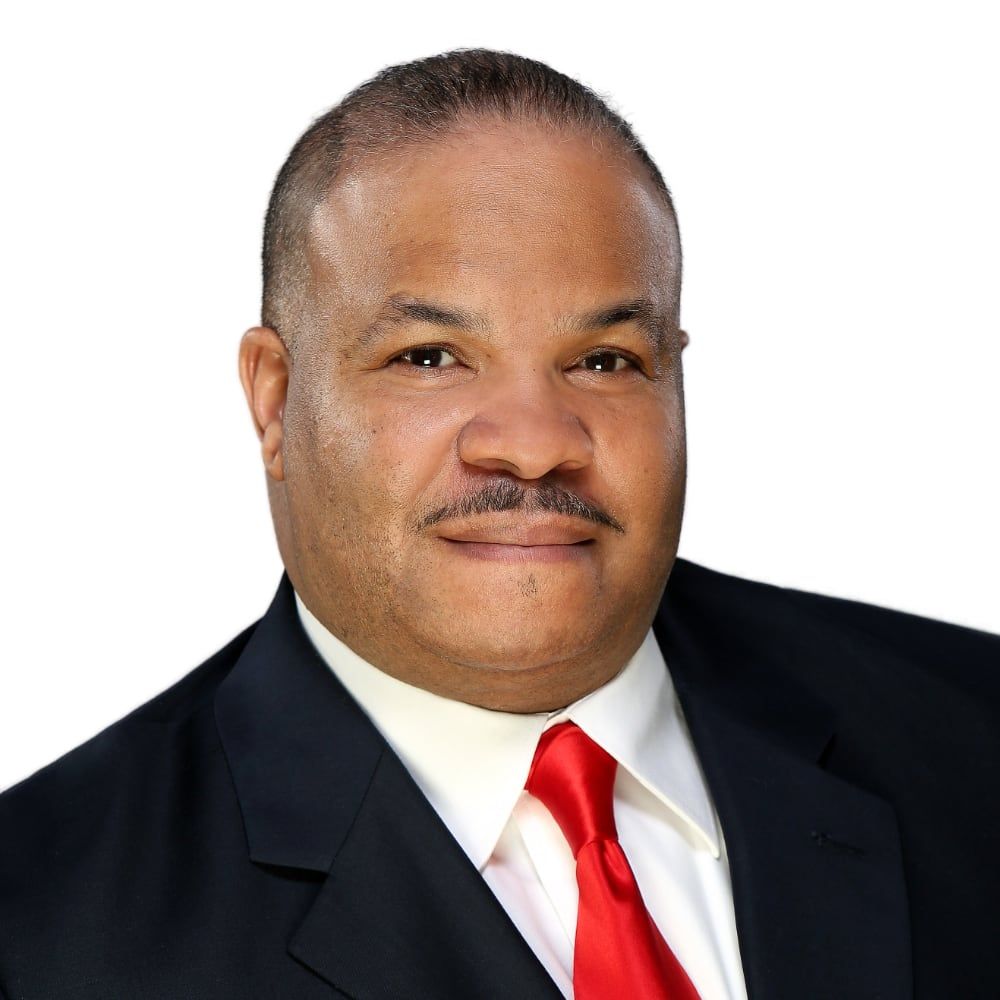 Smiling man in a gray suit and red tie against a white background