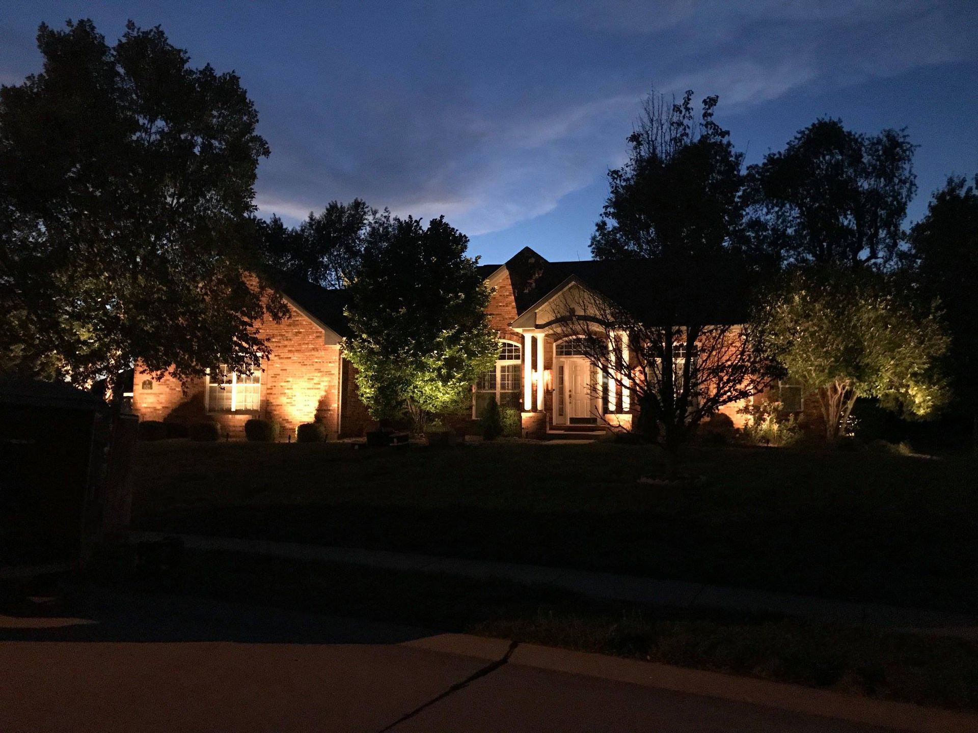 Lit house at night with trees and warm exterior lights