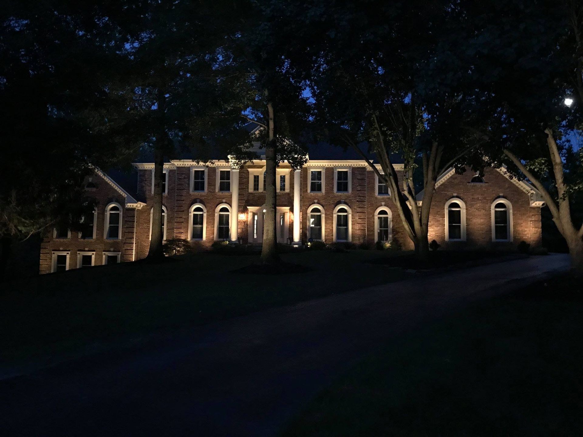 Illuminated brick building at night with arched windows and trees in front