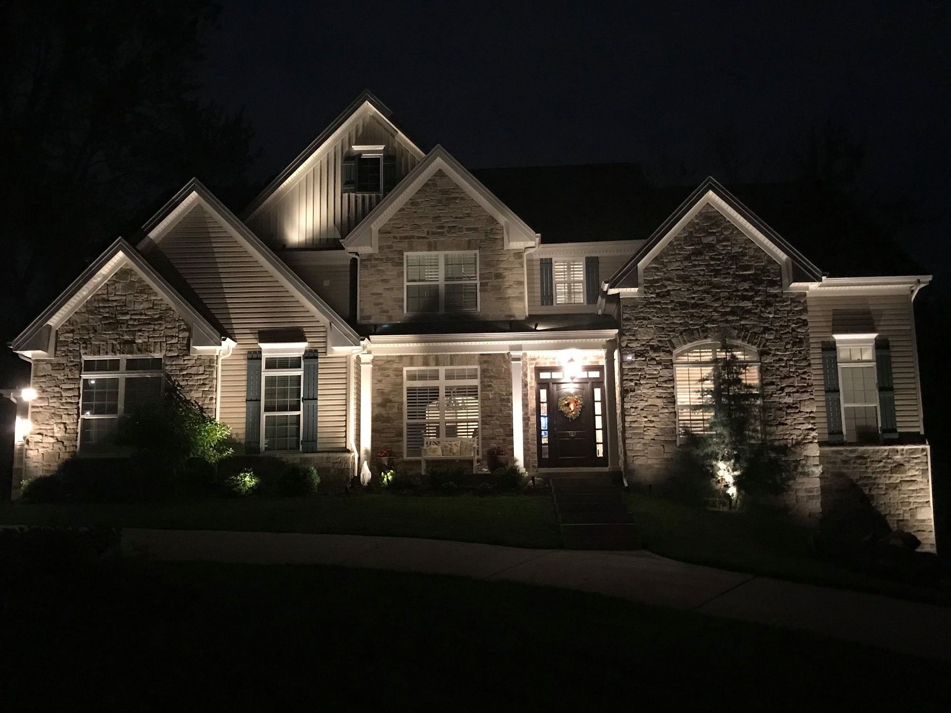 Worker installing outdoor wall lights on a brick wall at night