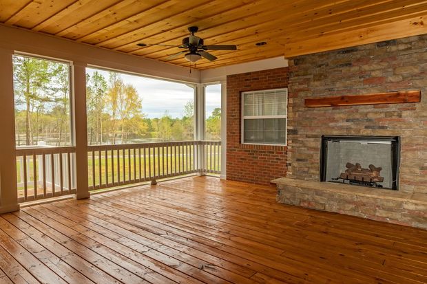 Covered porch with fireplace, wooden ceiling and floor, overlooking a body of water. Covered porch with fireplace, wooden ceiling and floor, overlooking a body of water.