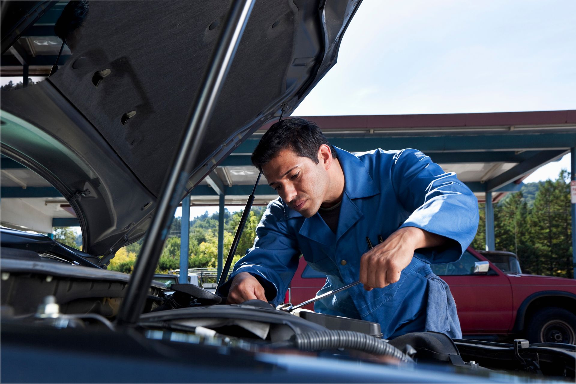 A man is working on a car with the hood open