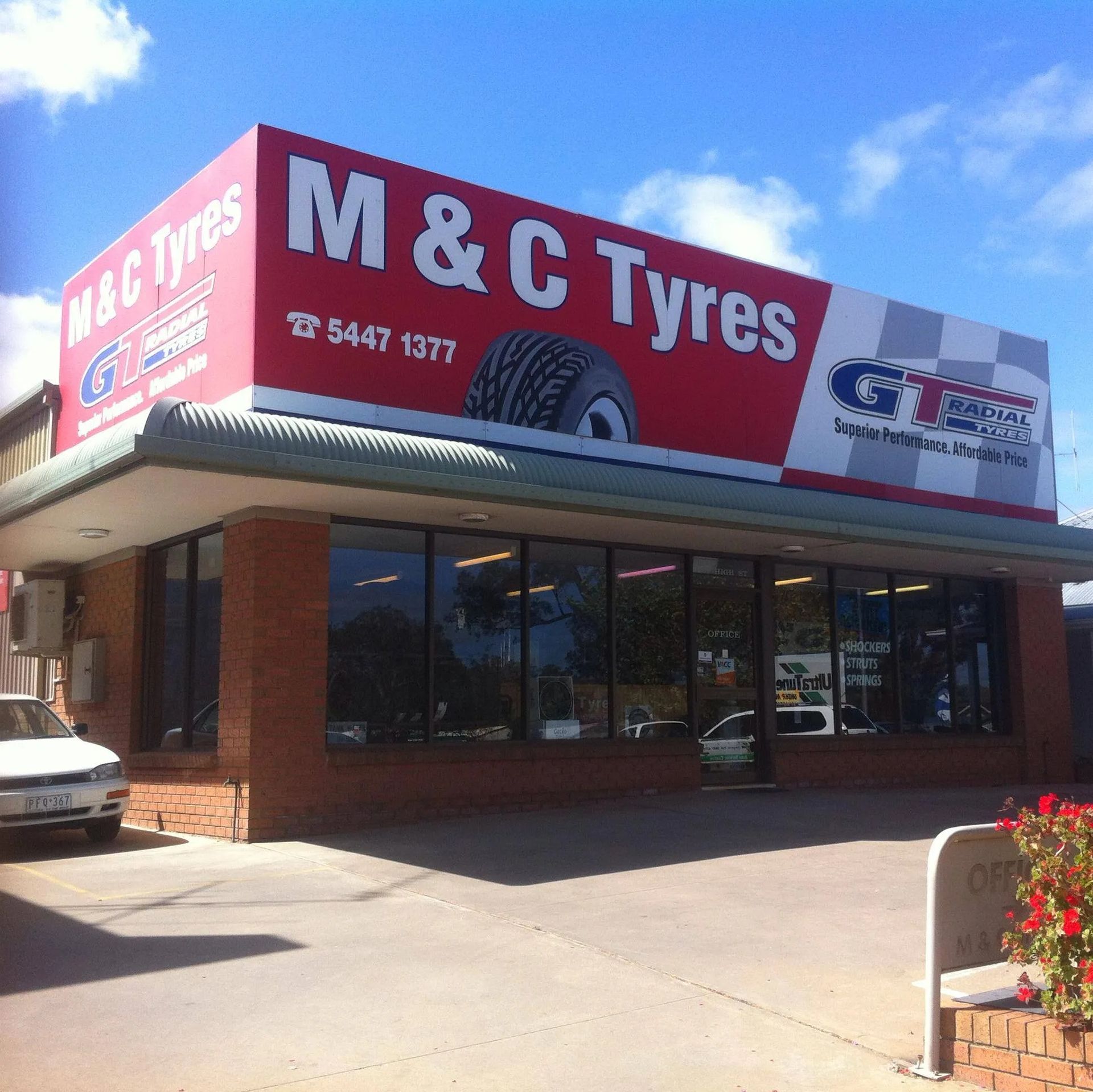M & C Tyres store with a red and white sign, a tire graphic, and a brick facade.