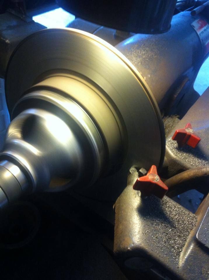 A brake rotor being machined on a lathe. The metal spins, creating a reflective surface.