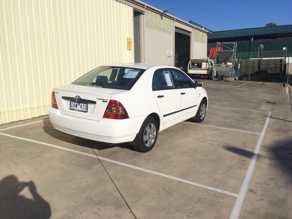 White Toyota Corolla parked in a parking space in front of a building.