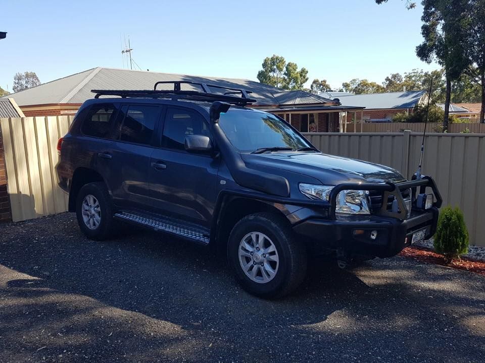 Dark blue SUV with roof rack, brush guard, and snorkel parked in driveway.