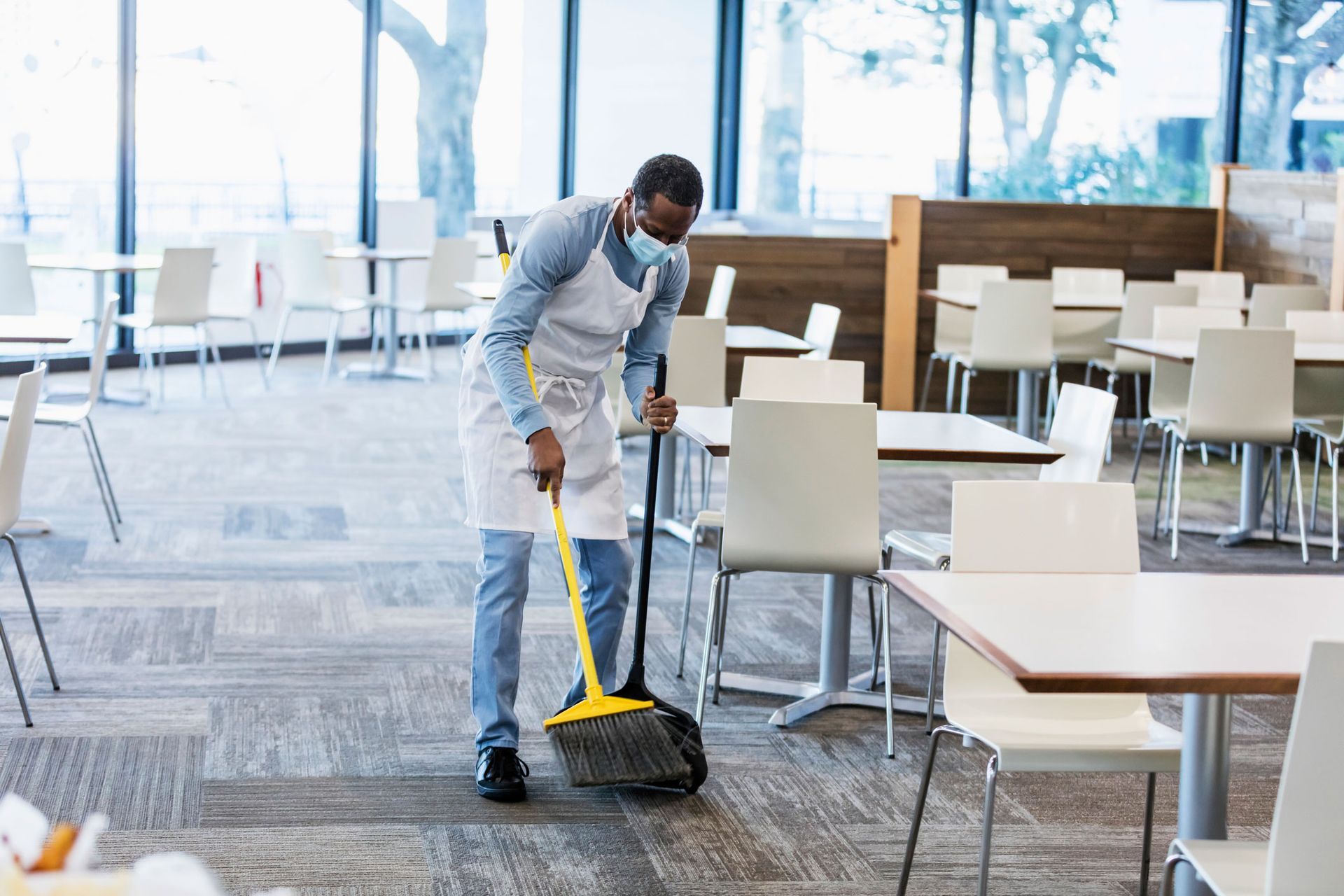 A man is cleaning the floor of a restaurant with a mop.