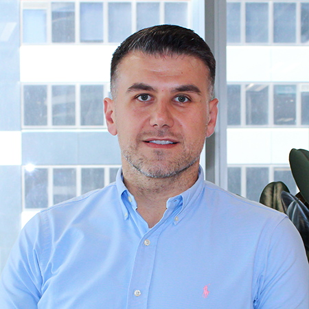 A man in a blue shirt is sitting in front of a window.