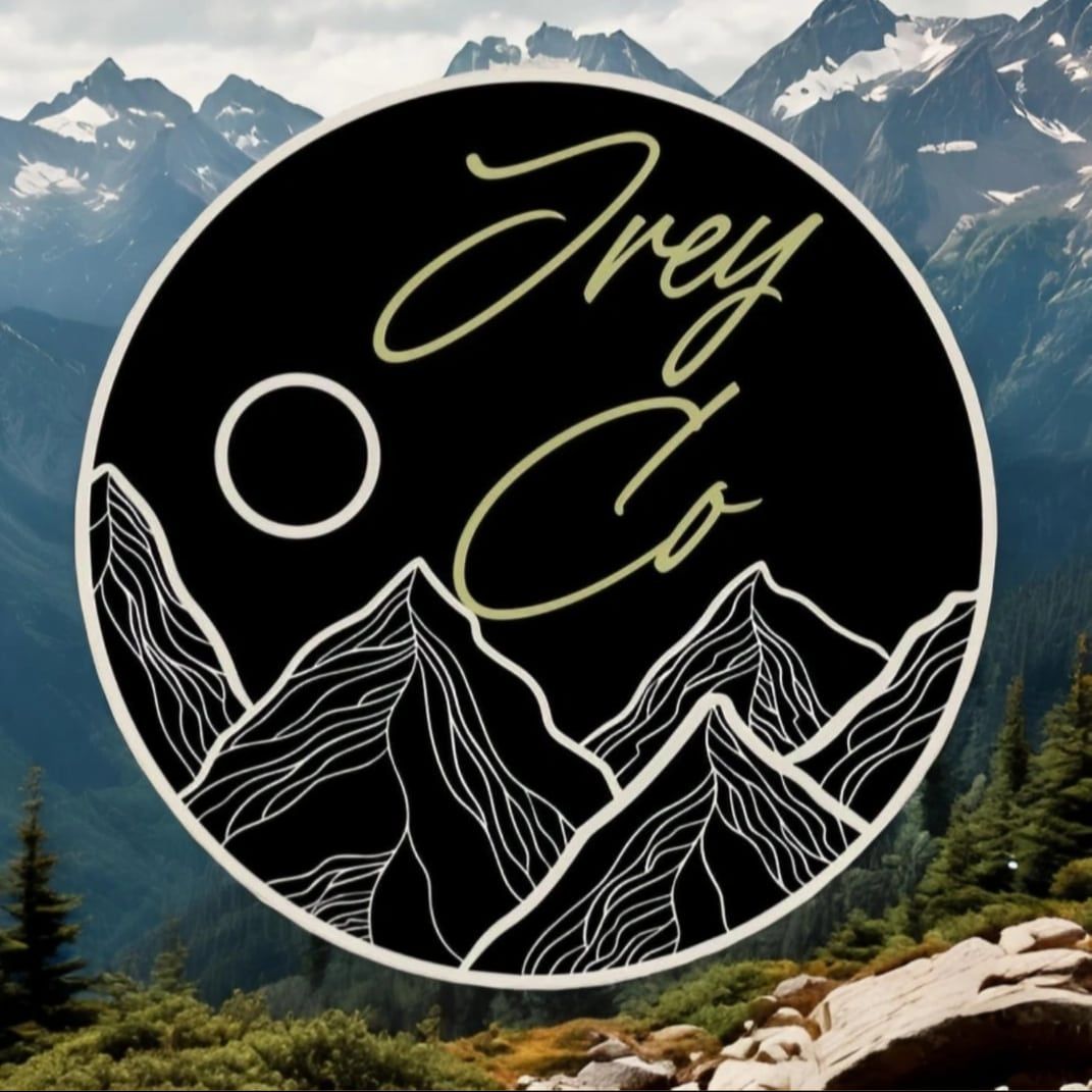 Black circular logo with cursive text over white line-art mountains and moon, set against a mountain landscape.