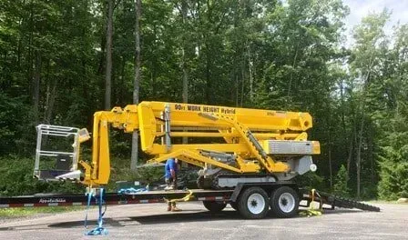 A Yellow Crane is Parked on a Trailer in a Parking Lot — Julian, PA — Aikey’s Tree Service A Yellow Crane is Parked on a Trailer in a Parking Lot — Julian, PA — Aikey’s Tree Service